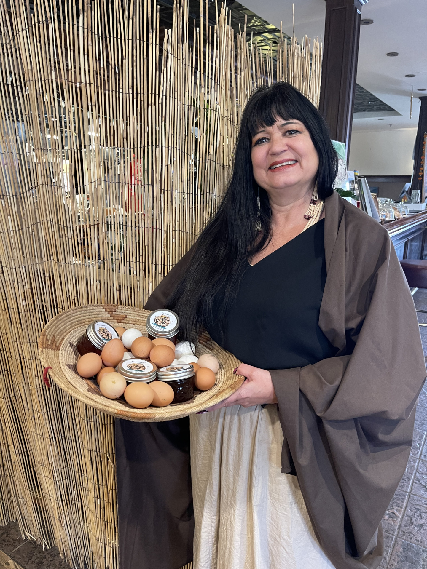 Woman standing inside holding a basket full of farm fresh eggs